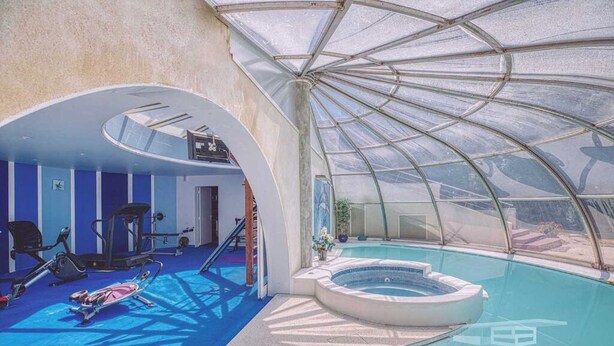 A gym with exercise equipment, a swimming pool, and a glass-enclosed area. - INDEPENDENT ROOM IN A PARK (Saint-Roch)