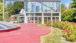 A modern glass conservatory with a red pathway leading to the entrance. - INDEPENDENT ROOM IN A PARK (Saint-Roch)