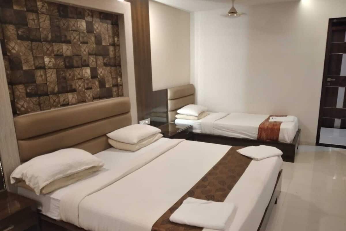 A hotel room with two beds, a stone wall, a ceiling fan, and a door with a mirror.