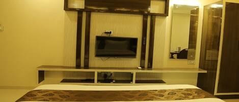 Una camera d'albergo con un letto, una TV a muro, uno specchio e un armadio.