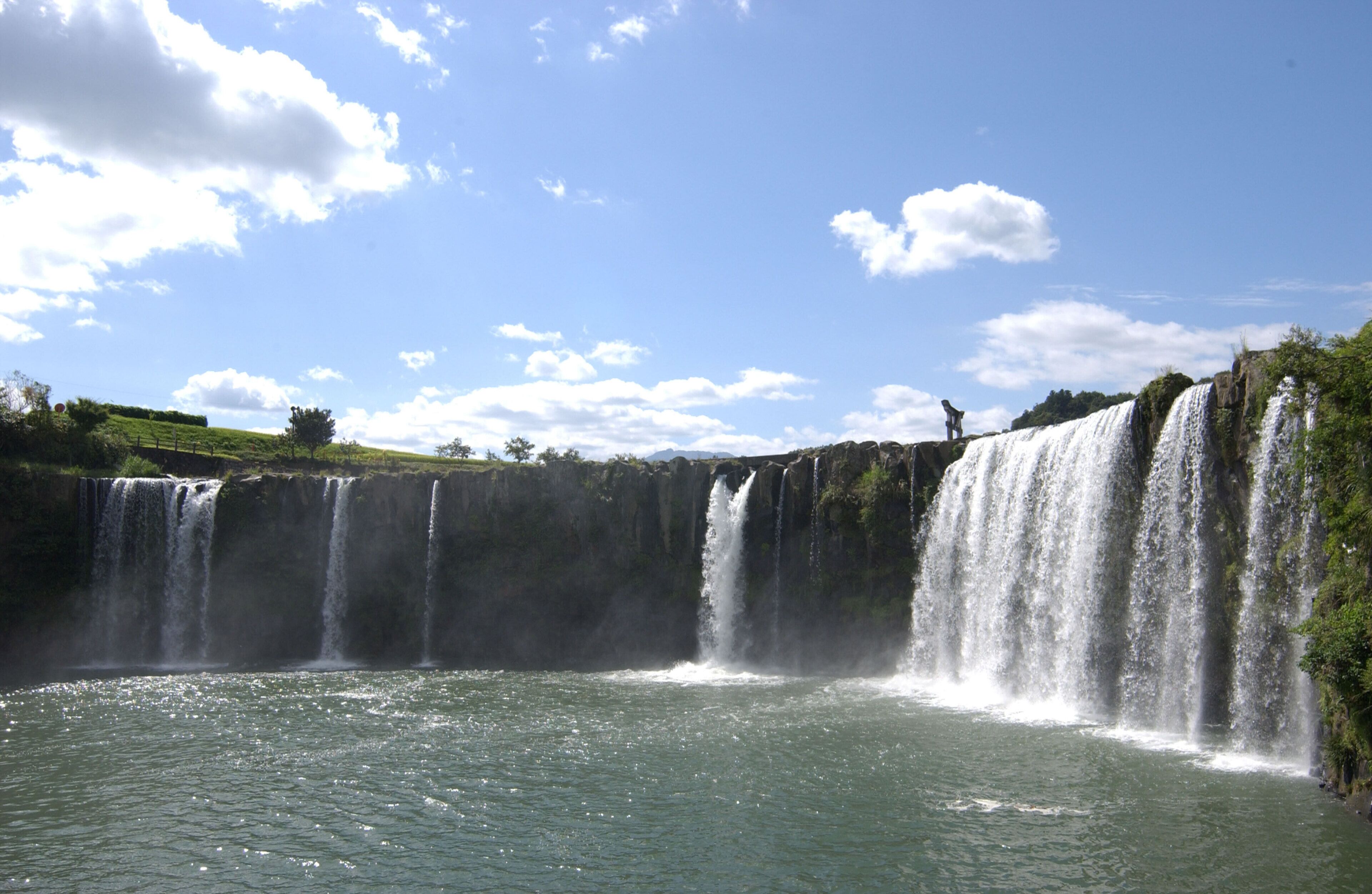 Una cascada vertiéndose en una masa de agua rodeada de vegetación.