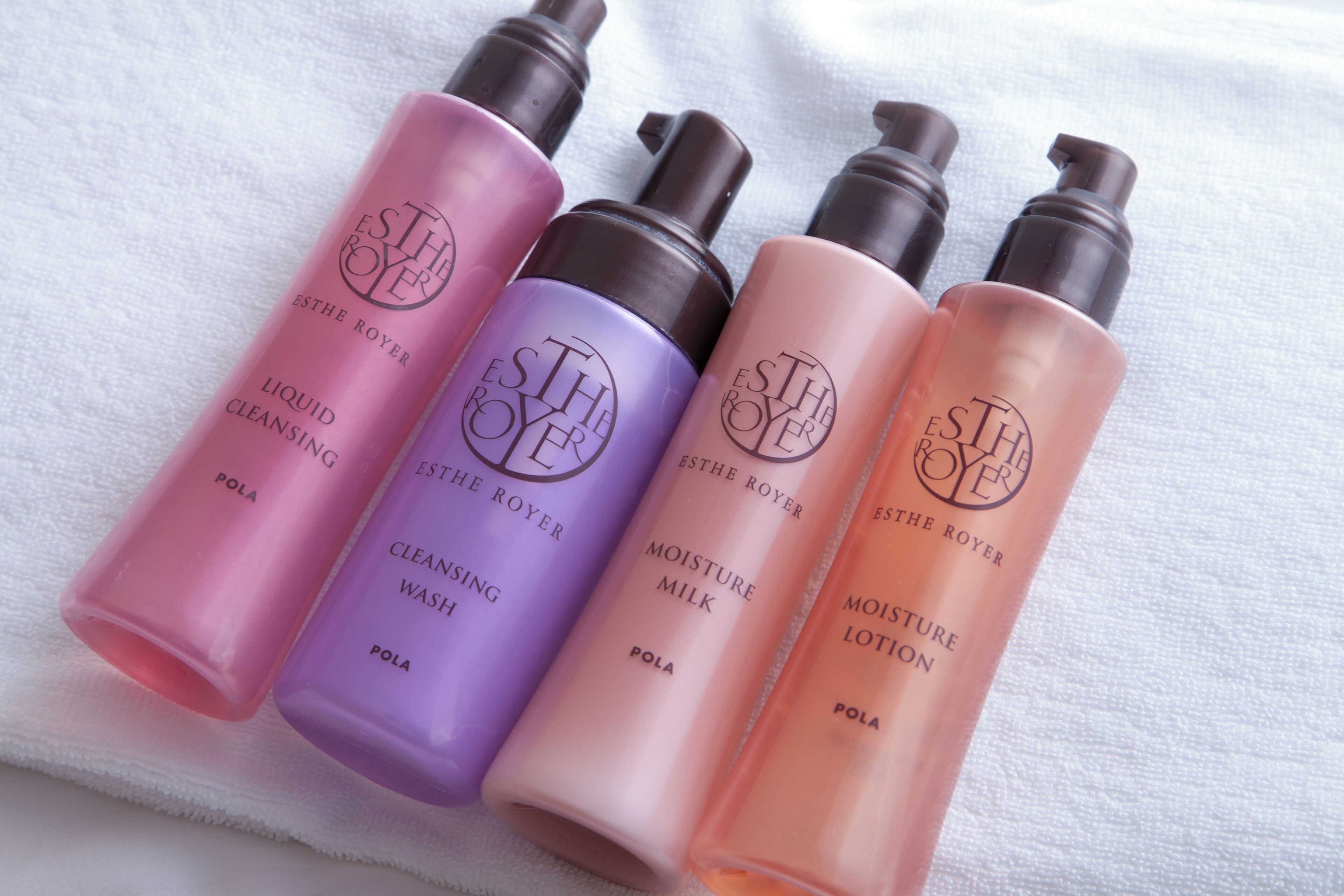 Four bottles of ESTHE ROYER skincare products on a white towel.