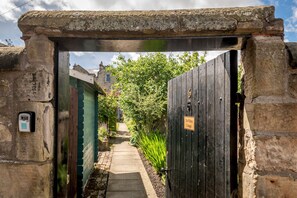 A stone archway leading to a gated entrance labeled 'The Whites Cottages.' - The Whins Cottage | St Andrews (St Andrews)