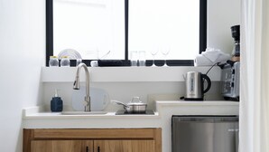 Una cocina moderna con un lavamanos de acero inoxidable, una cafetera y un hervidor en la encimera.