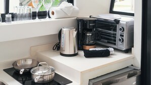 Una kitchenette con estufa, ollas, cafetera, tostadora y ventana con vista.
