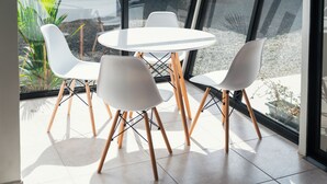 A modern indoor seating area with a round table and four white chairs with wooden legs.