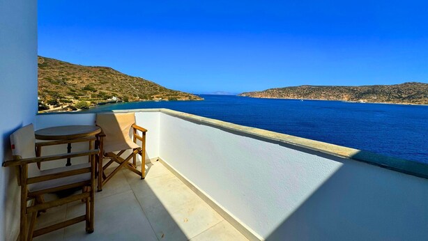 Ein Balkon mit Blick auf Meer und Hügel.