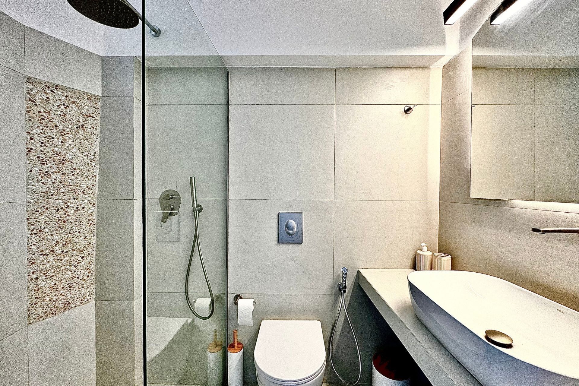 Une salle de bain moderne avec une douche à parois de verre, des toilettes et un meuble-lavabo avec un miroir.
