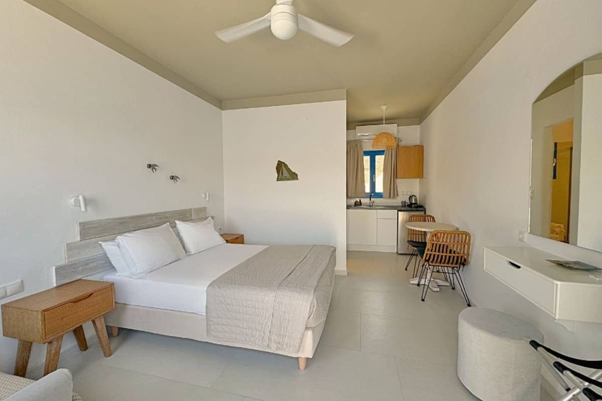 A modern hotel room with a bed, bedside table, and a small seating area.
