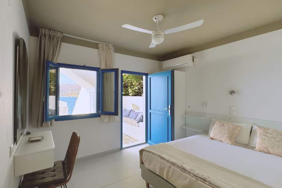 A bedroom with a bed, a chair, a desk, a ceiling fan, and a window with curtains.