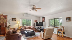 A living room with a sectional sofa, a chair, a coffee table, a TV, and a ceiling fan.