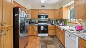 A kitchen with wooden cabinets, stainless steel appliances, and a tiled backsplash.