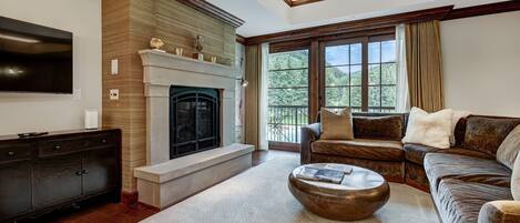 A living room with a fireplace, a large window, and a sofa.
