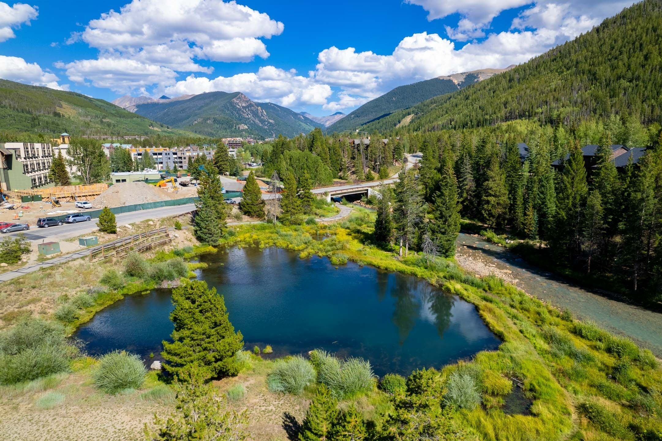 A mountainous landscape with a lake, a bridge, and a road with vehicles.