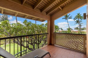 Un espacio al aire libre techado con vista a un jardín y palmeras.