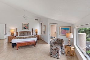 A bedroom with a bed, bedside tables, a chair, a window, and artwork on the walls. - Wailea Ekahi, #19a 2 Bedroom Condo by RedAwning (Kihei)