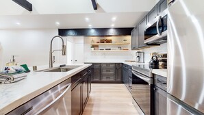 A modern kitchen with stainless steel appliances, a marble countertop, and dark cabinetry. - Bigwood #96 2 Bedroom Condo by RedAwning (Mammoth Lakes)