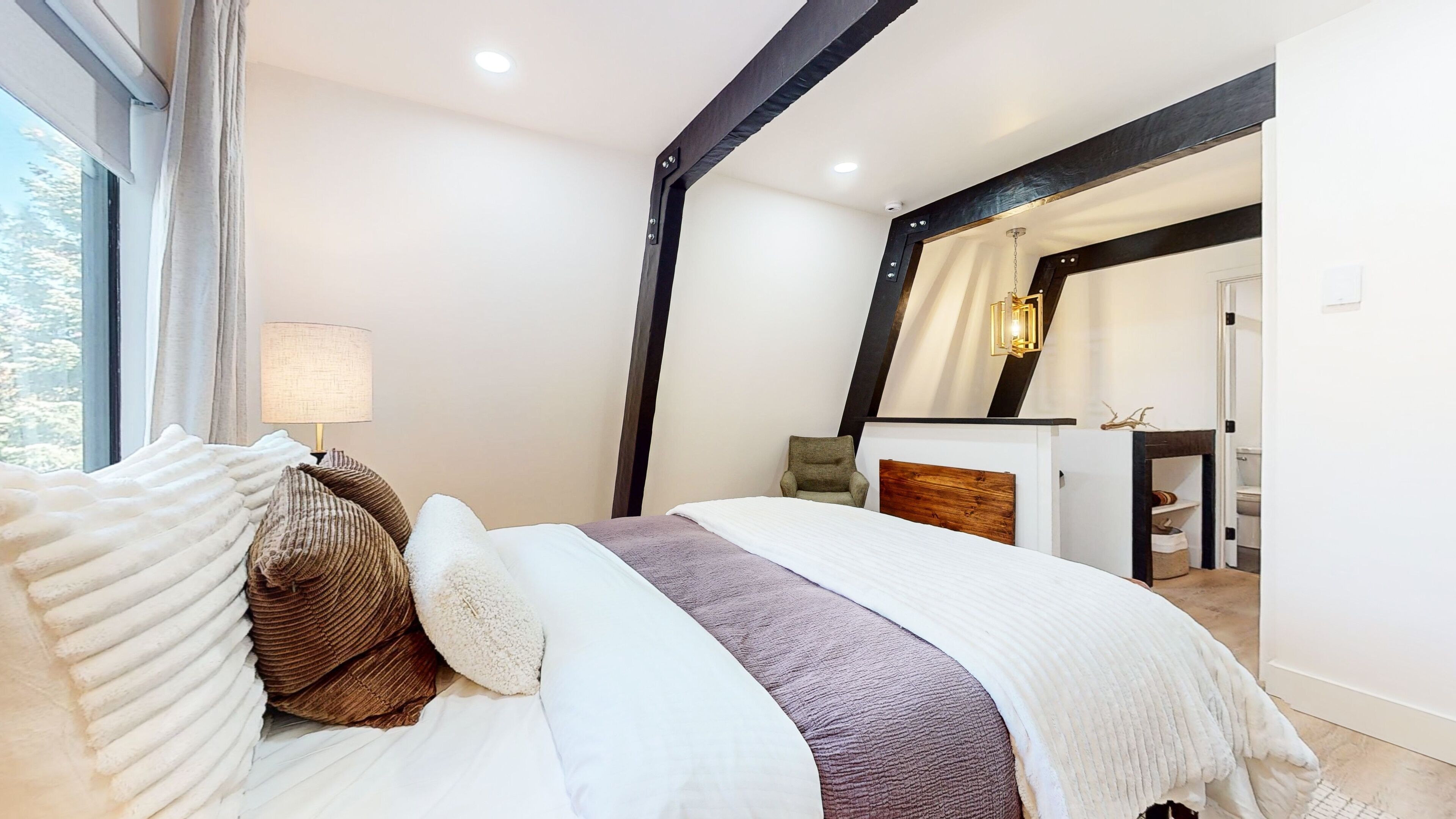 Un dormitorio con una cama grande, una lámpara de noche y vistas al baño.
