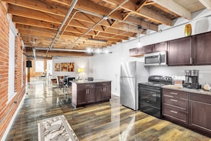 A spacious kitchen with dark wooden cabinets, stainless steel appliances, and a polished hardwood floor.