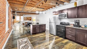 A spacious kitchen with dark wooden cabinets, stainless steel appliances, and a polished hardwood floor. - Stylish Chic Retreat At Lafayette Lofts 1 Bedroom Apts by RedAwning (Detroit)
