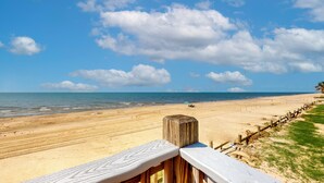 A beach with a wooden fence, a sandy shore, and a clear sky.