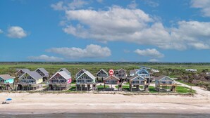 A beachfront property with multiple houses, a sandy beach, and a clear sky.