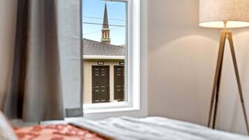 Une chambre d’hôtel avec une fenêtre donnant sur une église et une lampe.