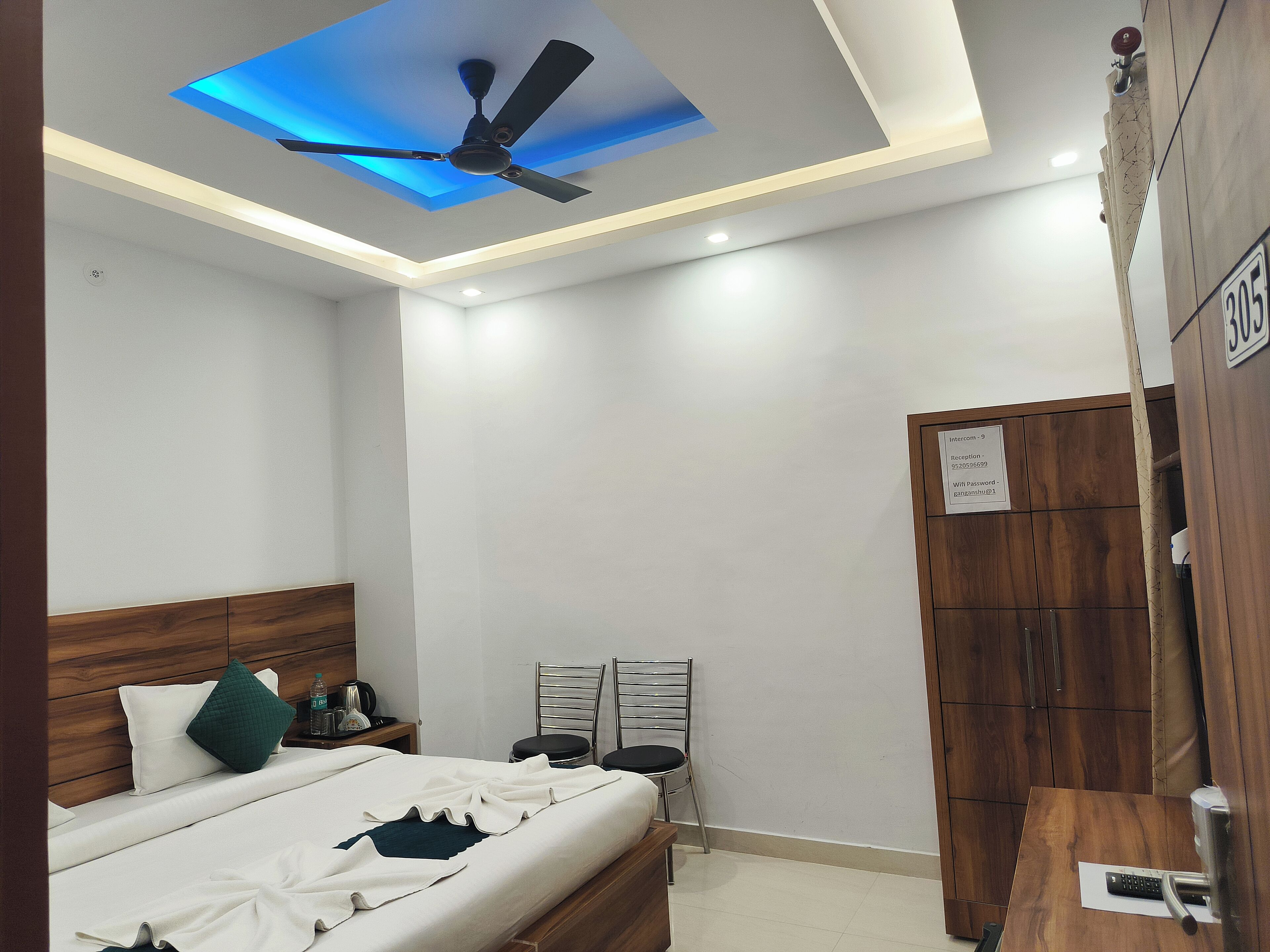 A modern bedroom with a bed, bedside tables, a ceiling fan, and a wooden wardrobe.
