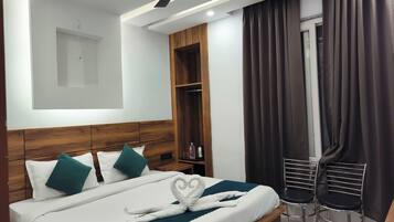 Una camera d'albergo moderna con un letto ben rifatto, una ventola a soffitto, un minibar e un angolo salotto con due poltrone.