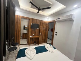 Una habitación de hotel con cama, escritorio, silla, televisor y armario.