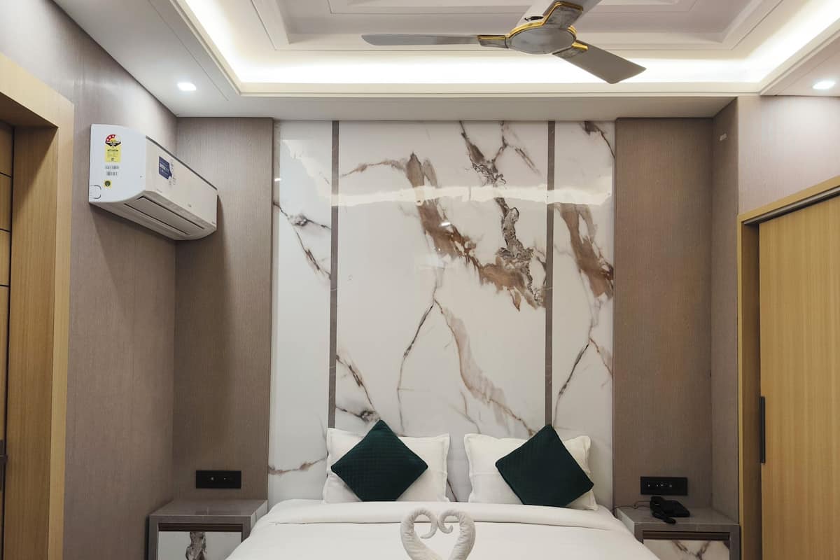 A modern hotel room with a marble headboard, a bed with white bedding and green pillows, a ceiling fan, and a bedside table with a phone.
