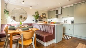 Une cuisine moderne dotée d’un îlot central, d’une table à manger en bois et d’un coin salon.