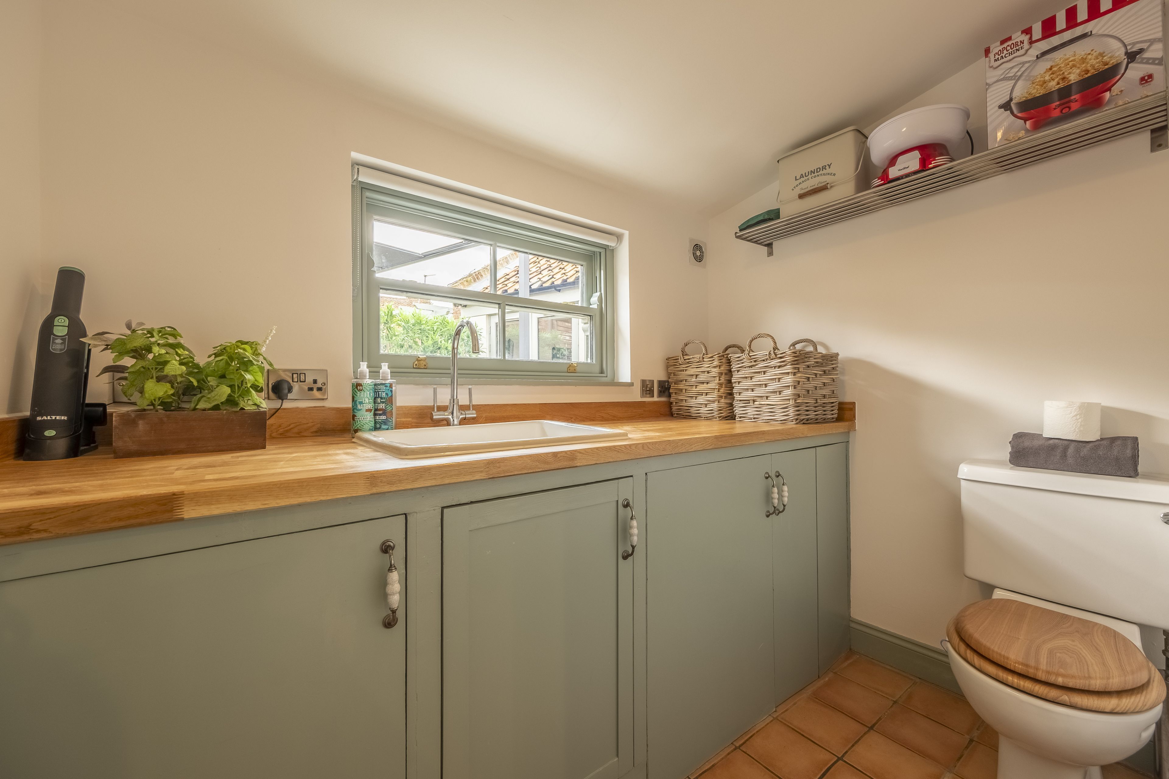 A compact kitchen with a window, a sink, and a toilet.