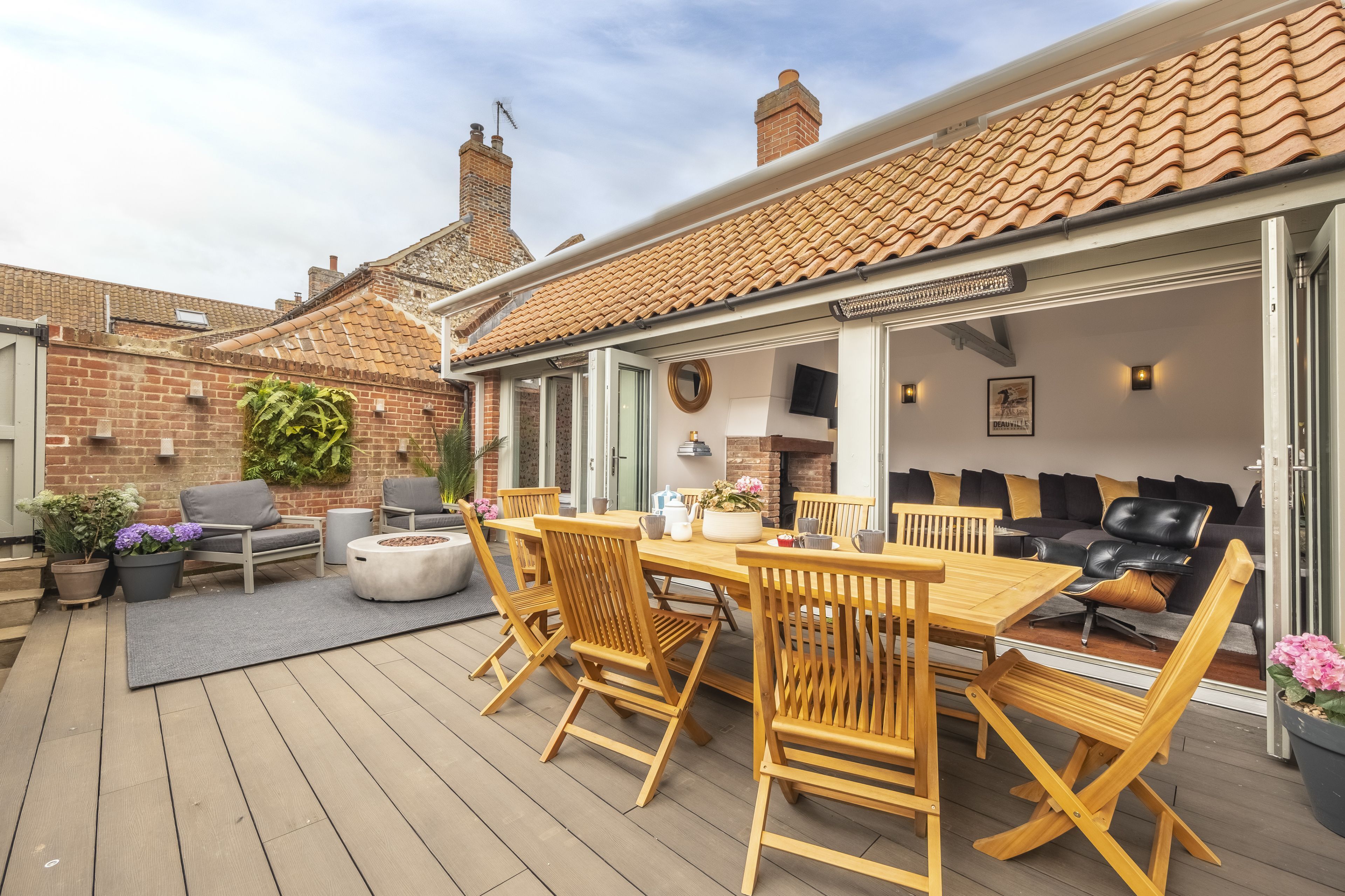 A patio with wooden furniture, a brick wall, and a tiled roof.
