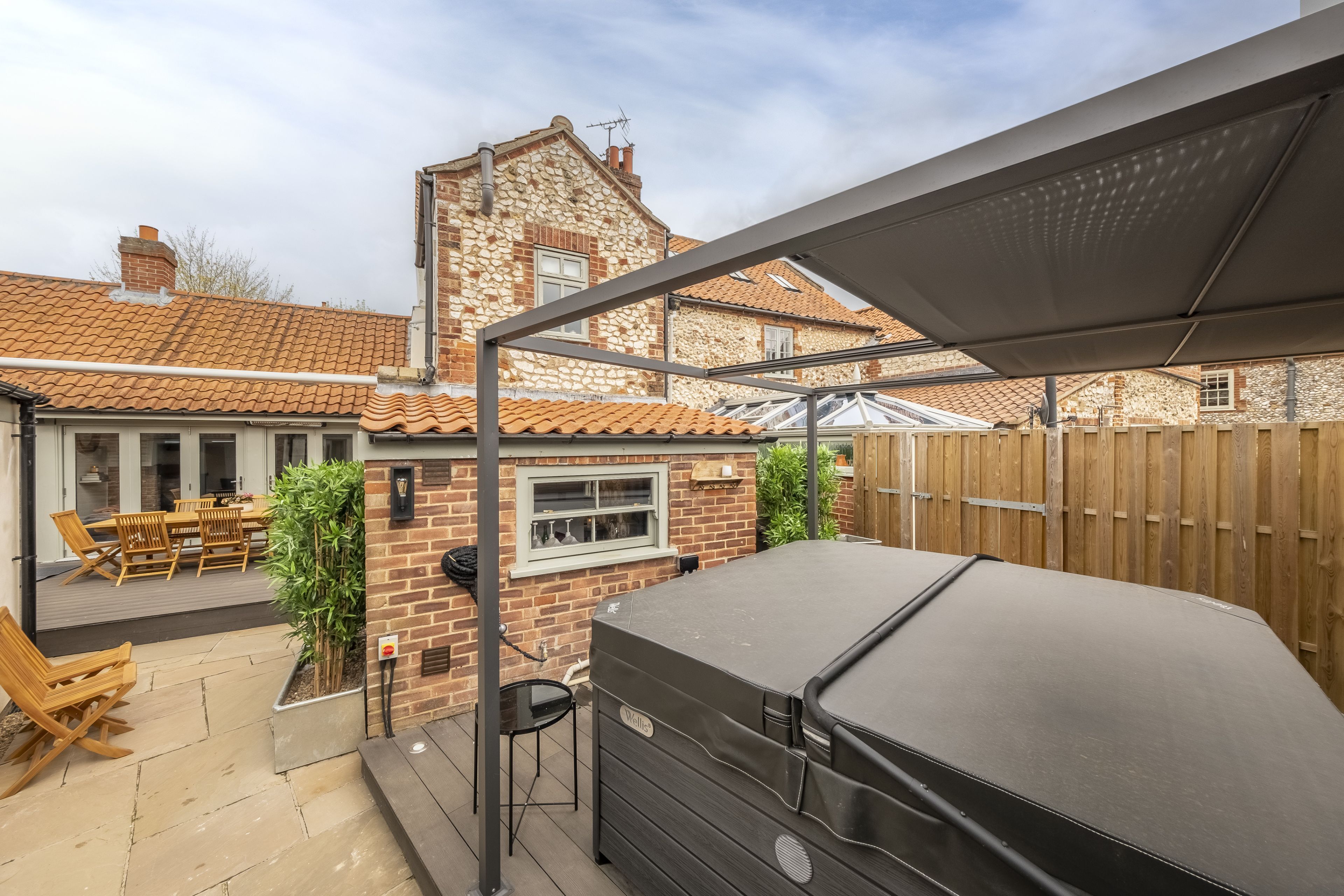 Une terrasse avec des meubles d’extérieur, un barbecue et un bâtiment en pierre en arrière-plan.