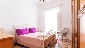 A bedroom with a bed, a chair, a wardrobe, and a bedside table. - 4187 Casa Elen by Barbarhouse (Ostuni)