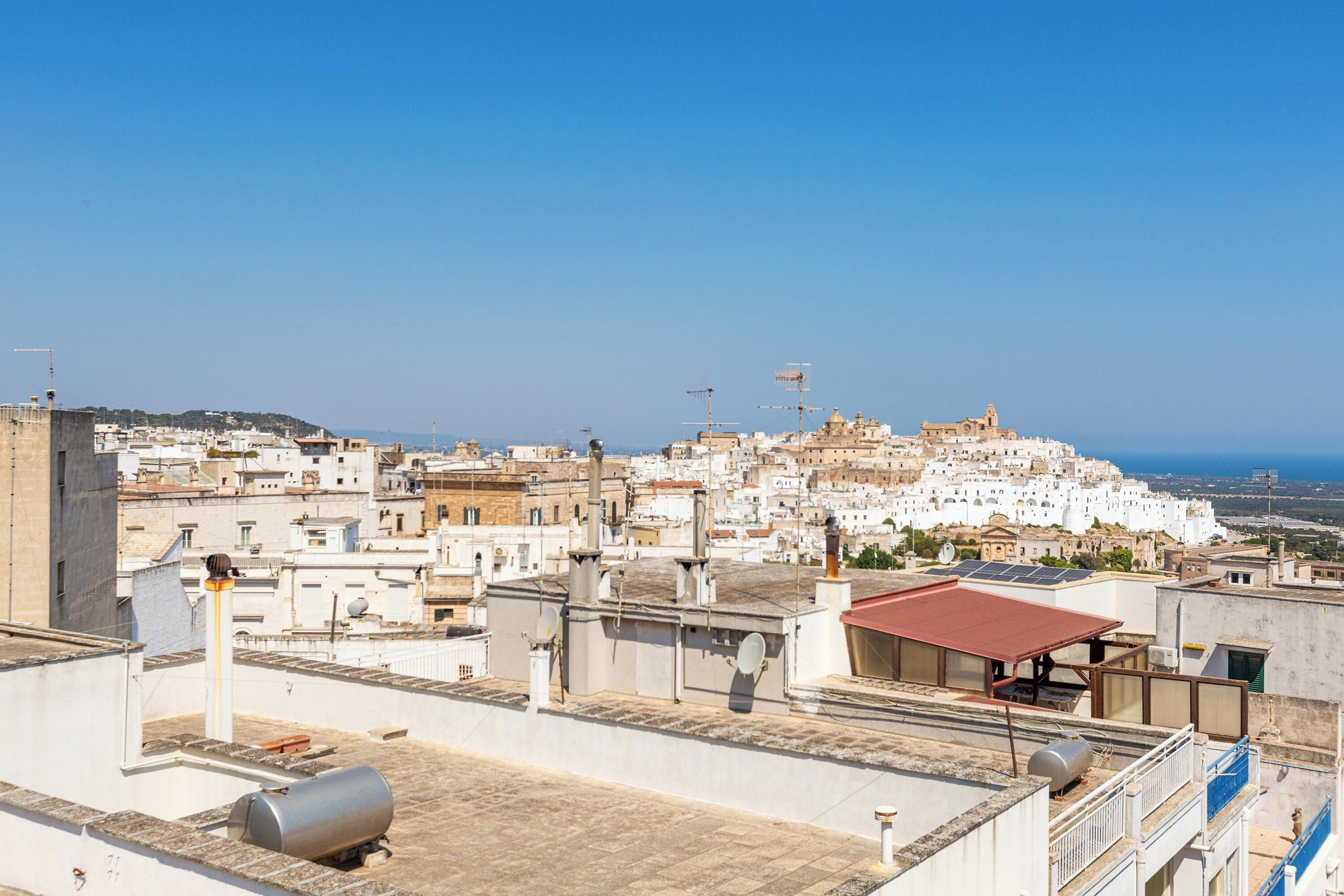 A cityscape with white buildings, a prominent church, and a clear blue sky.