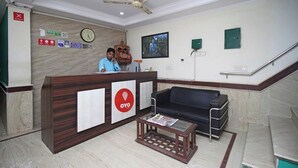 A reception area with a wooden desk, a clock, and a Buddha statue. - HOTEL SMART STAY (New Delhi)