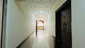A long, narrow hallway with a tiled floor and a dark door on the right. - HOTEL SMART STAY (New Delhi)