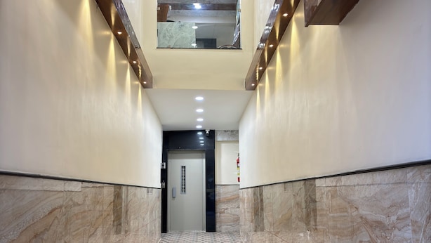 A hallway with a patterned floor, a door at the end, and a small window above. - Hotel Shreegopal (Ujjain)