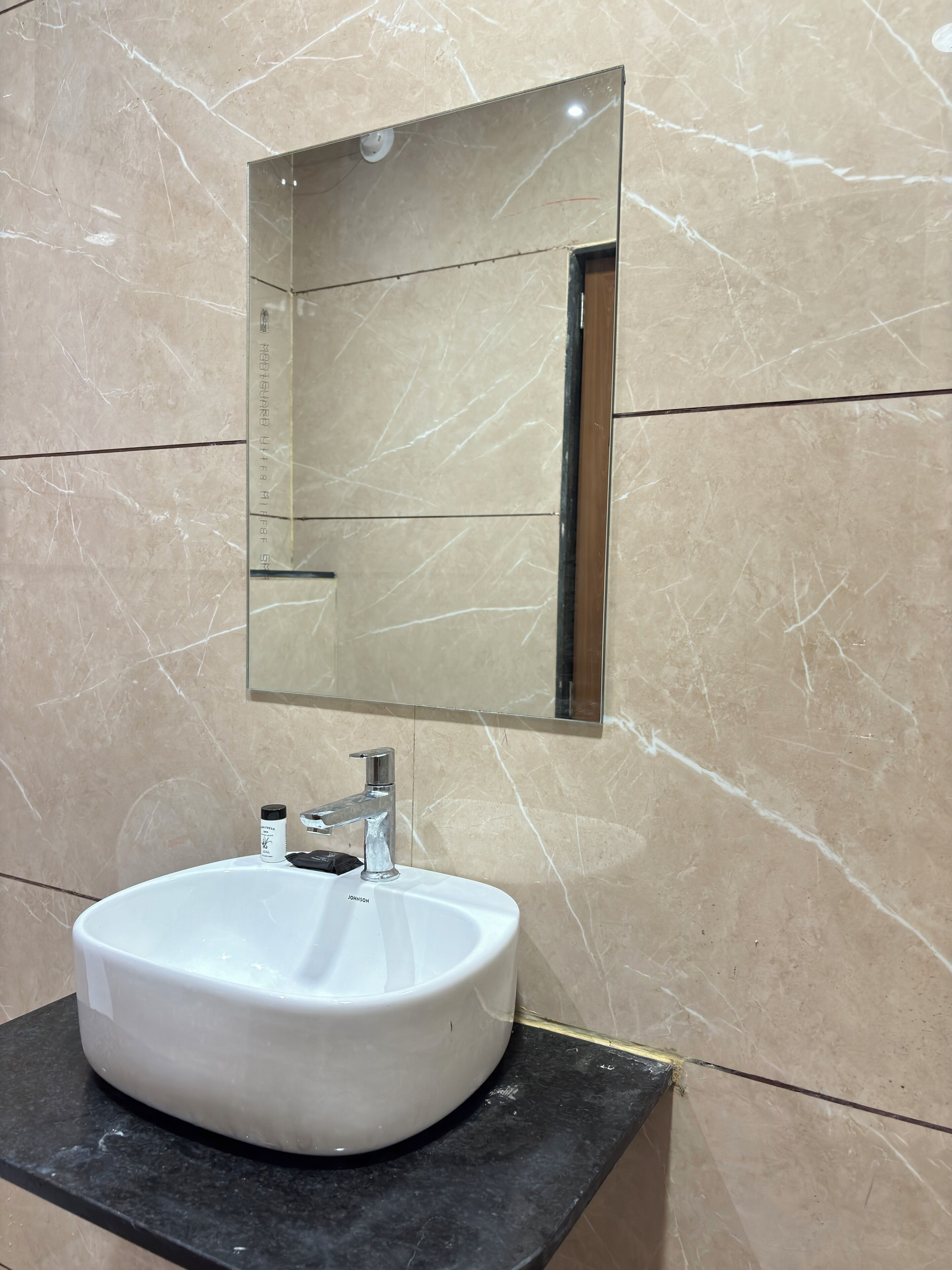A bathroom with a white sink, a mirror, and marble walls.