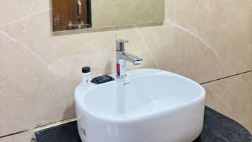 Un baño con lavamanos blanco, un espejo y un perchero para toallas.