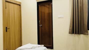 Un dormitorio con cama, aire acondicionado, puerta de madera y cortina.