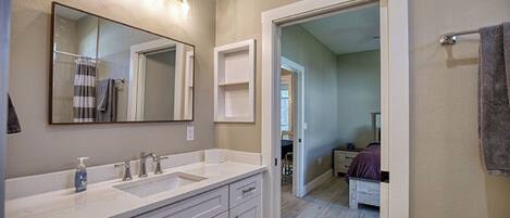A bathroom with two sinks, a large mirror, and a shower area.