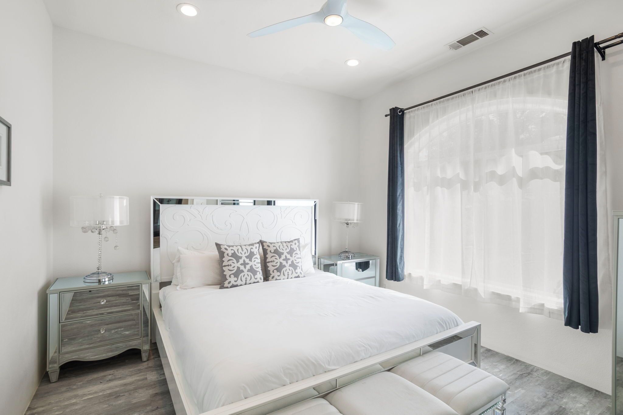 Un dormitorio moderno con una cama grande, mesitas de noche y un ventilador de techo.