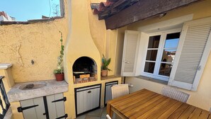 A compact outdoor kitchen area with a built-in grill, a sink, and potted plants.
