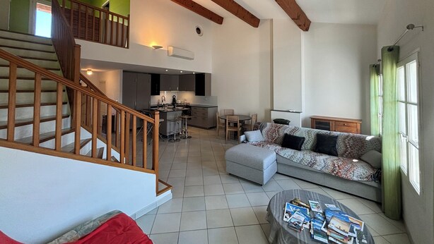 A spacious living area with a staircase, a kitchen, and a dining area.