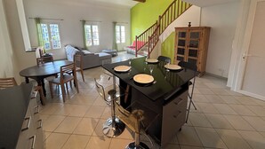 A spacious living area with a dining table, sofa, and a staircase leading to another level.