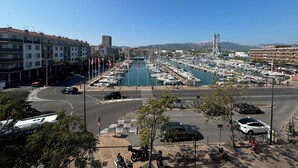 A marina with boats docked, a hotel named Mercure Hotel in the background, and a road intersection with vehicles and pedestrians.