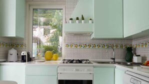 A kitchen with a gas stove, oven, and a window with a view of greenery.
